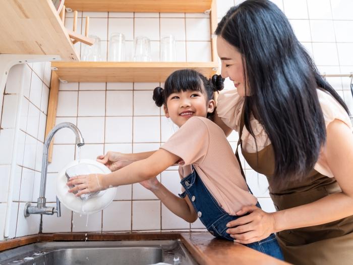 mom and daughter at kitchen sink washing dishes